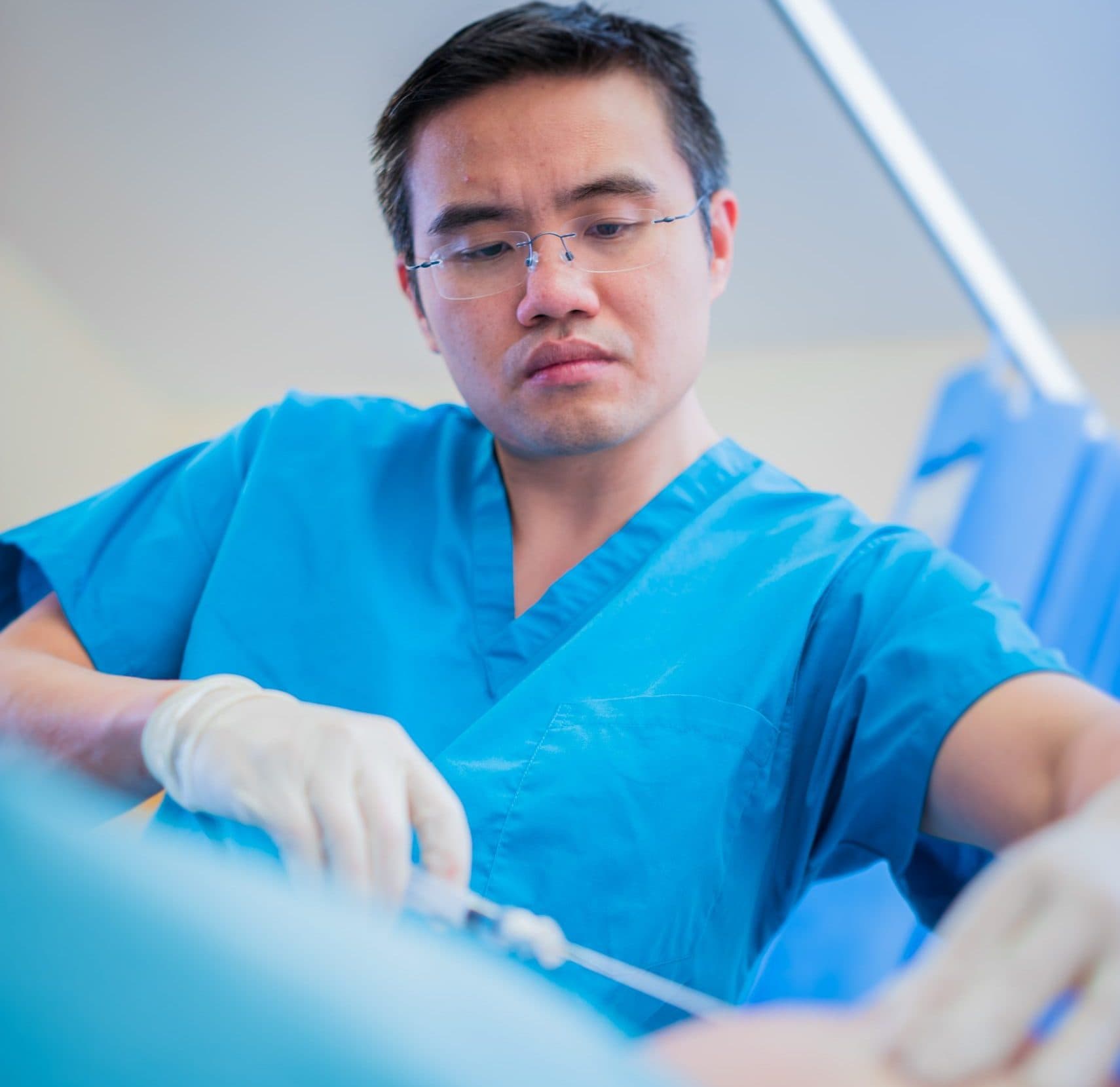 Doctor in blue scrubs focused during procedure